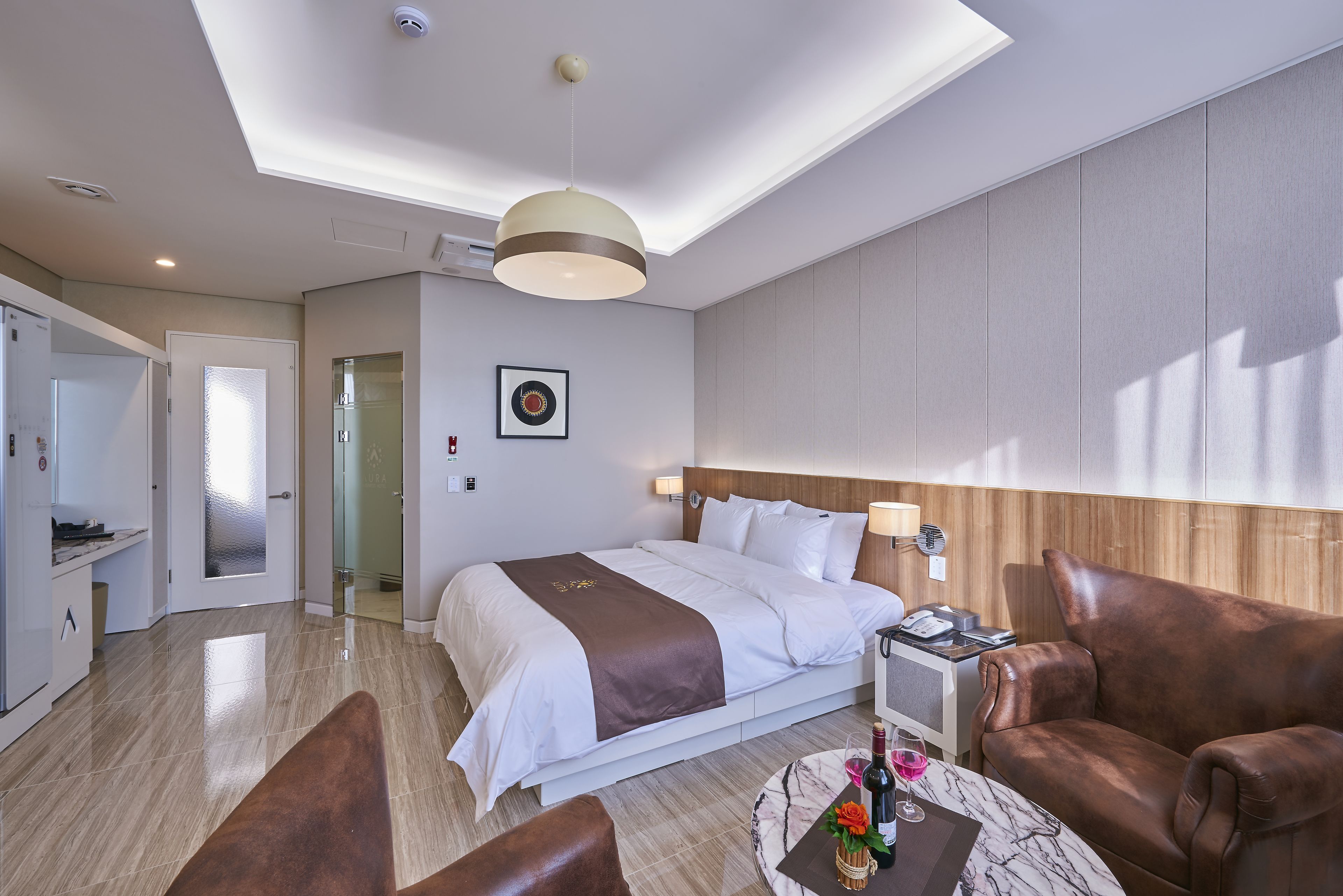 Hotelkamer met een groot bed, een bureau, een stoel en een kleine tafel met een fles en glas.