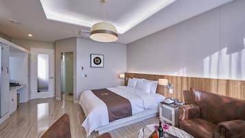 Hotelkamer met een groot bed, een bureau, een stoel en een kleine tafel met een fles en glas.