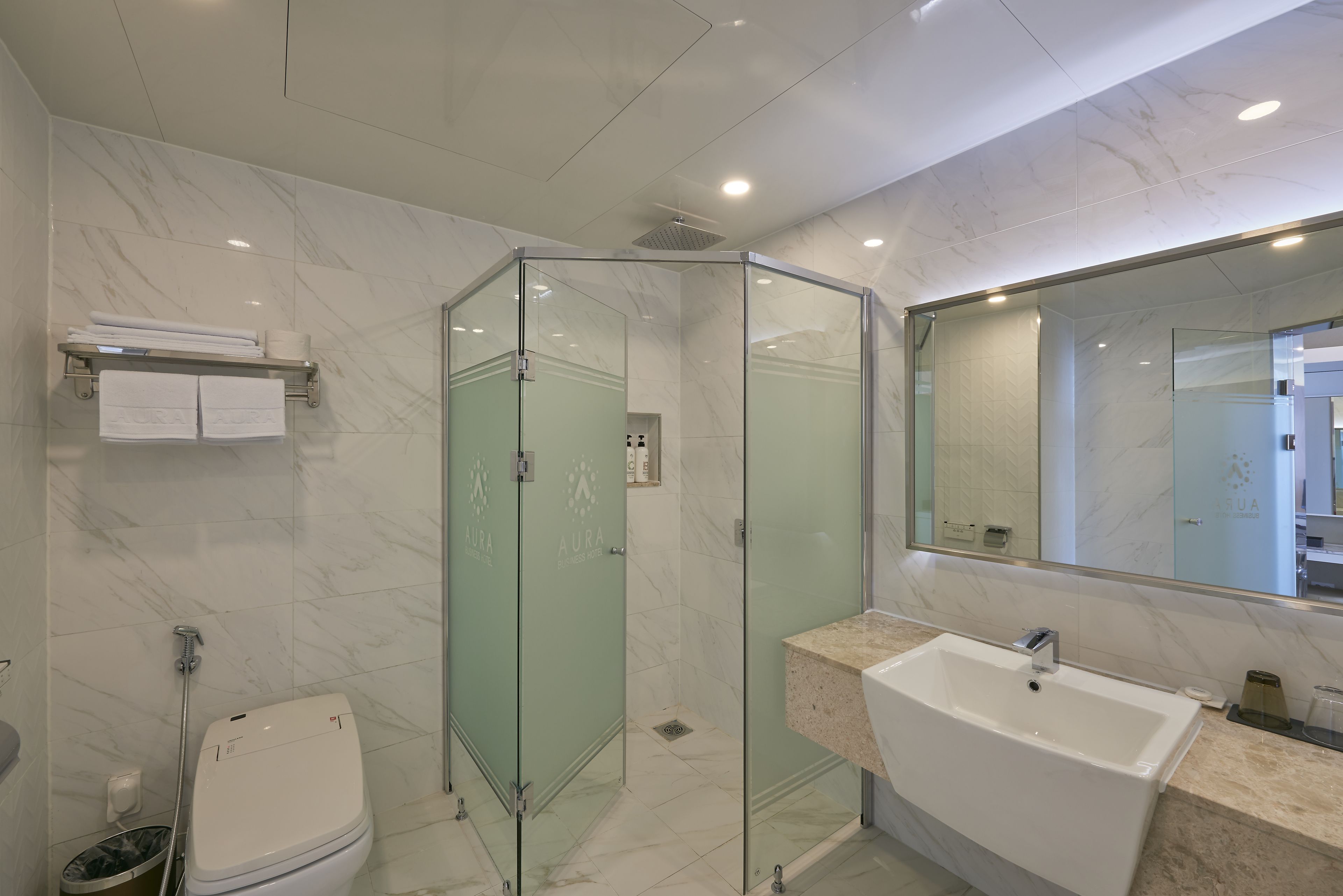 Une salle de bain moderne avec une douche à parois de verre, un lavabo blanc et un sol carrelé en marbre.