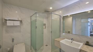 Une salle de bain moderne avec une douche à parois de verre, un lavabo blanc et un sol carrelé en marbre.