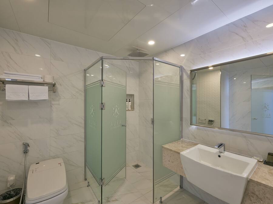 Une salle de bain moderne avec une douche à parois de verre, un lavabo blanc et un sol carrelé en marbre.