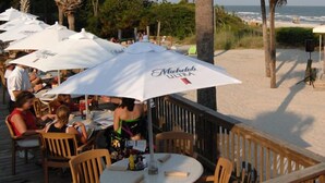 Terraza exterior con sombrillas, vista al mar y escenario para música en vivo.