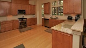 Cocina moderna con armarios de madera, electrodomésticos de acero inoxidable y un amplio ventanal que proporciona luz natural.