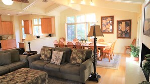 Una sala de estar con sofá, reposapiés y un comedor con sillas y una mesa.