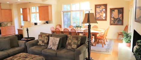 A living room with a sofa, ottoman, and dining area with chairs and a table.