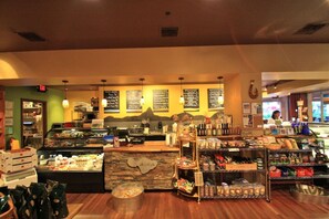 A restaurant interior with a counter, menu boards, and a display of food items. - Beautiful Ocean View on Quiet Side of Honua Kai (Lahaina)