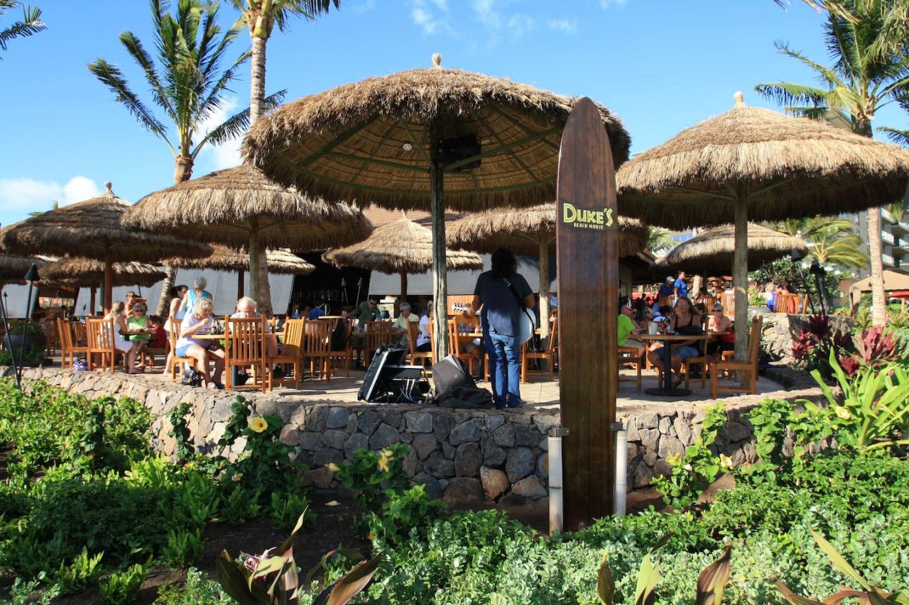 An outdoor dining area with thatched umbrellas and stone walls.