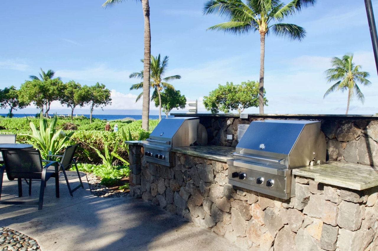 Un espace barbecue extérieur avec des murs en pierre et une vue sur l’océan.