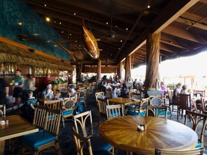 An indoor restaurant with wooden furniture and a thatched roof. - Beautiful Ocean View on Quiet Side of Honua Kai (Lahaina)