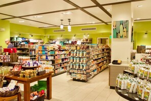 A grocery store with various aisles of products, a checkout counter, and a man browsing the shelves.
