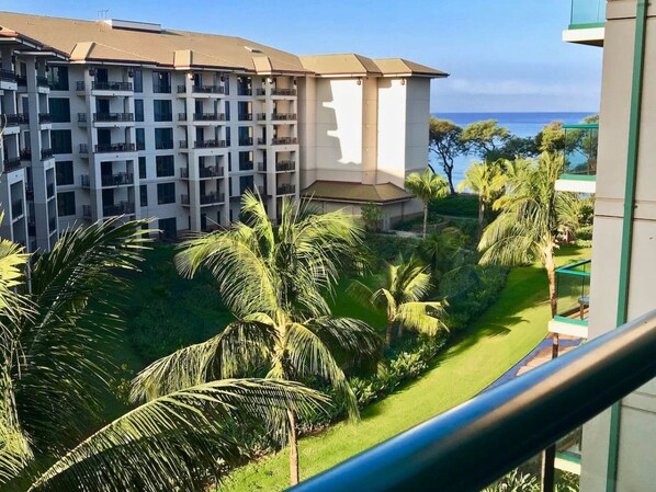 Un hôtel à plusieurs étages doté de balcons donnant sur un espace paysager agrémenté de palmiers et offrant une vue sur l’océan.
