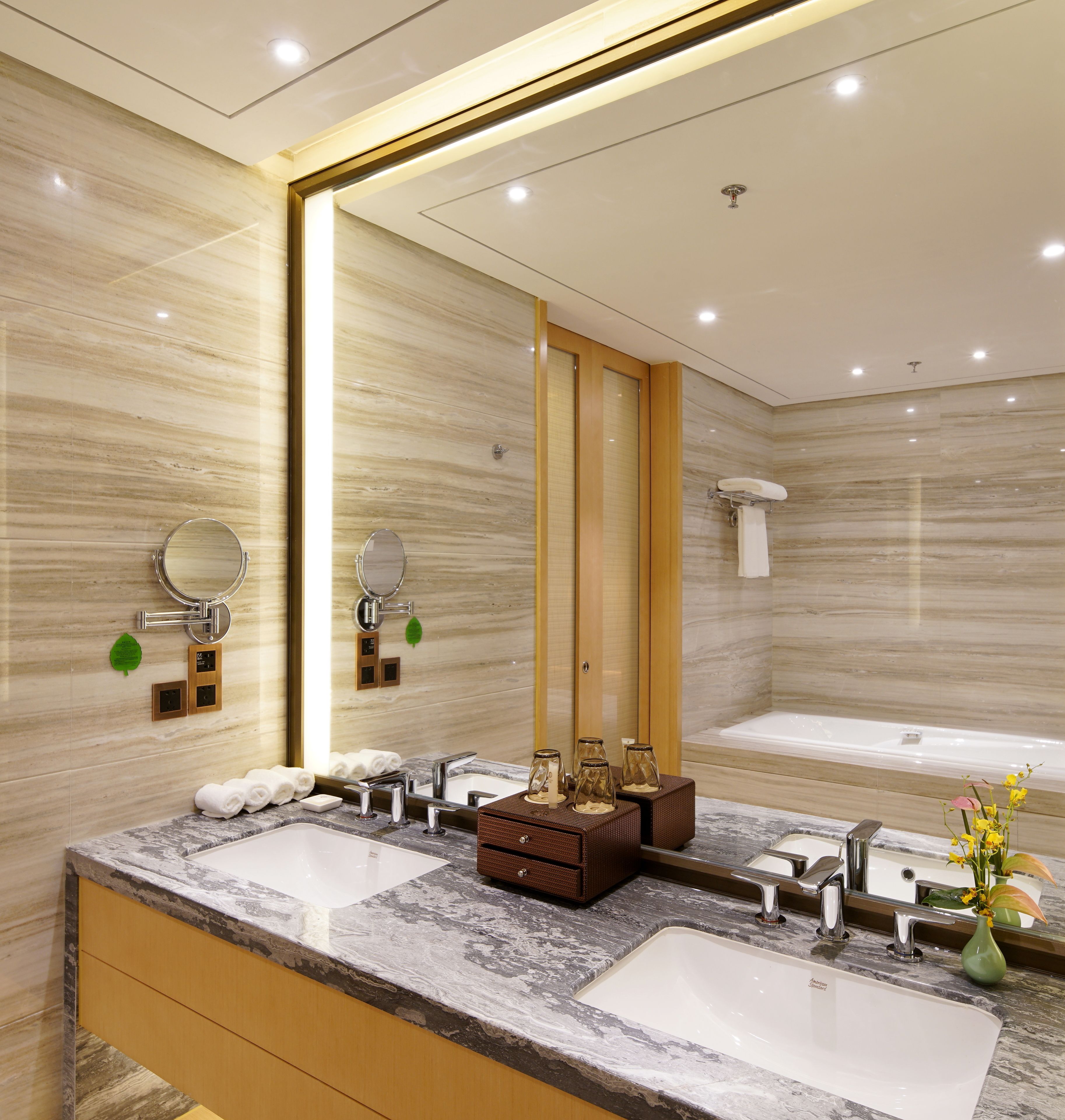Un baño moderno con dos lavamanos, un espejo grande y una bañera.