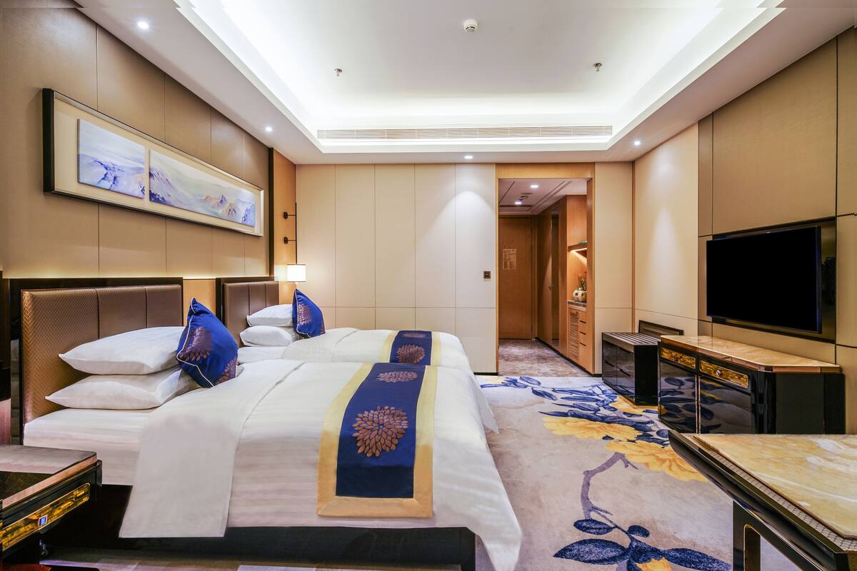 A hotel room with a large bed, a flat-screen TV, a desk, and a walk-in closet.
