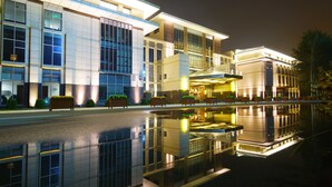 A modern hotel with a reflective pool, large windows, and a well-lit facade. - Qingshan Hotel Baotou（Yingbin Building） (Baotou)