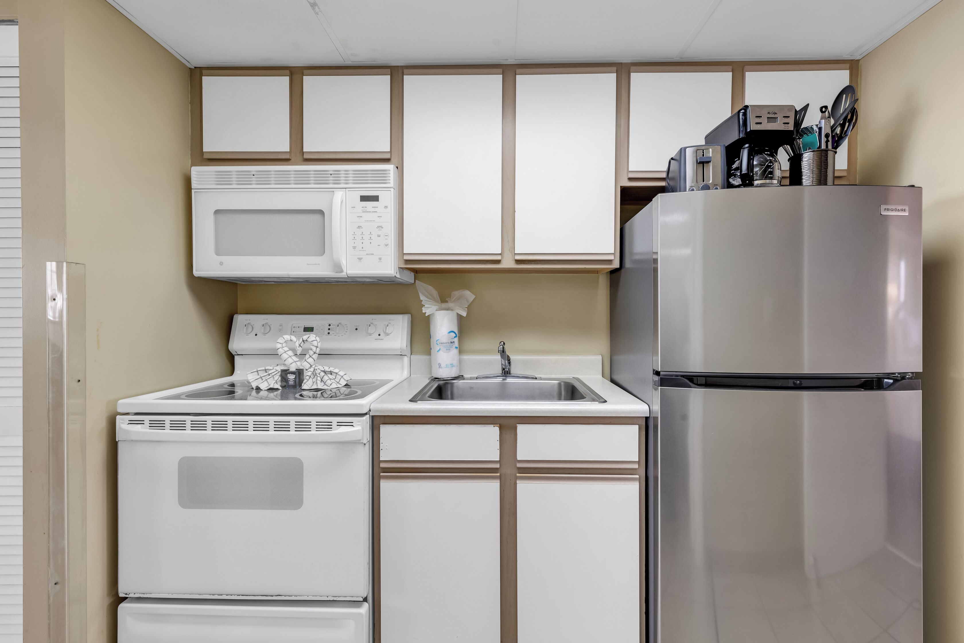 A compact kitchen with a microwave, stove, sink, and refrigerator.