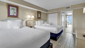 Quarto de hotel com duas camas, uma escrivaninha e vista para a varanda.