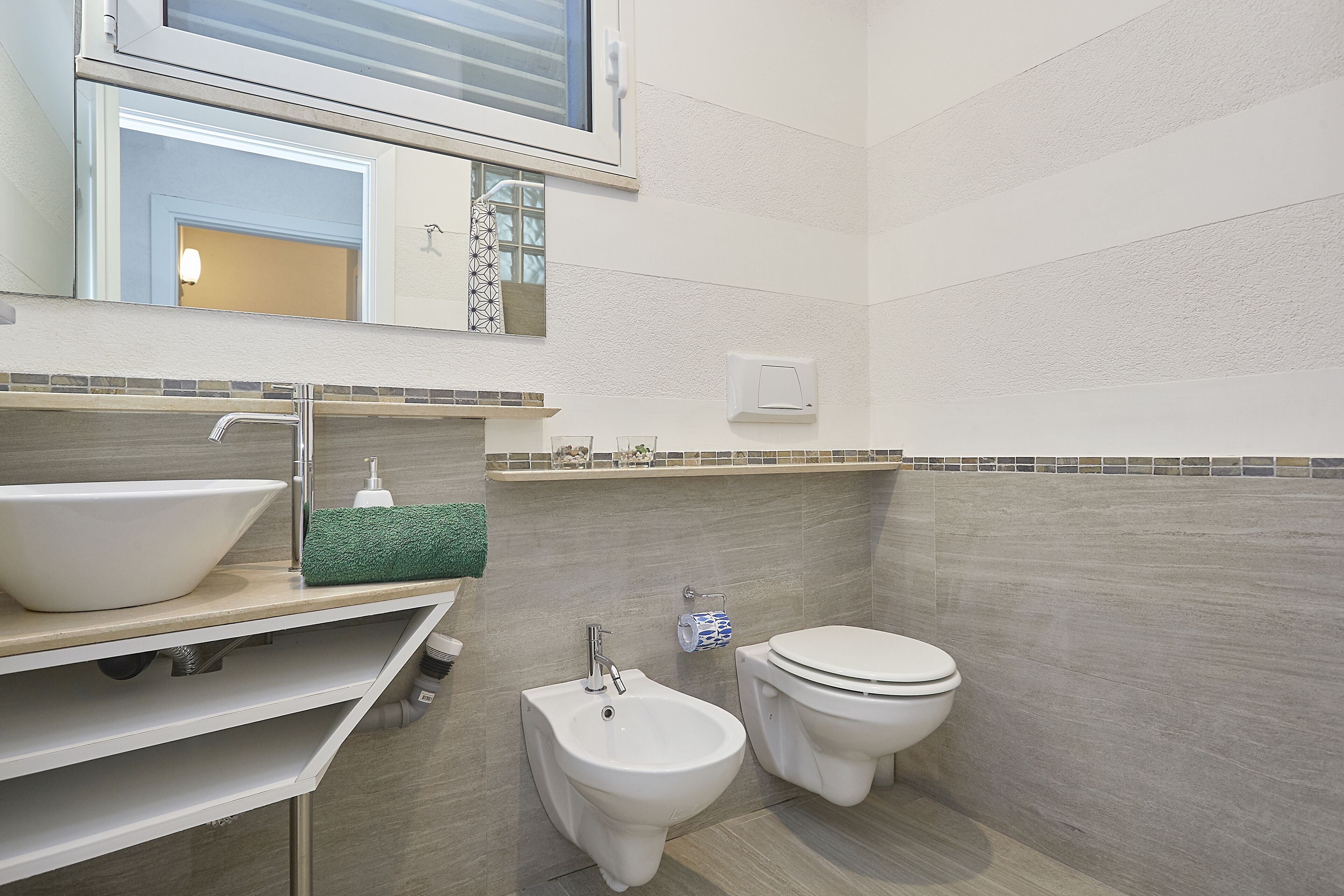 A modern bathroom with a large sink, bidet, and toilet.