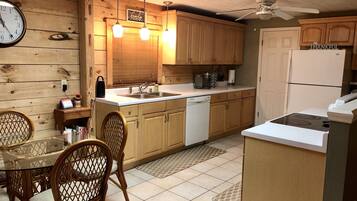 Una cocina con armarios de madera, lavavajillas, refrigerador y comedor con sillas y una mesa.