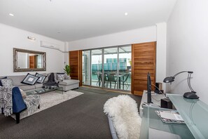 Uma sala de estar moderna com sofá, mesa de centro e escrivaninha de vidro com um computador.