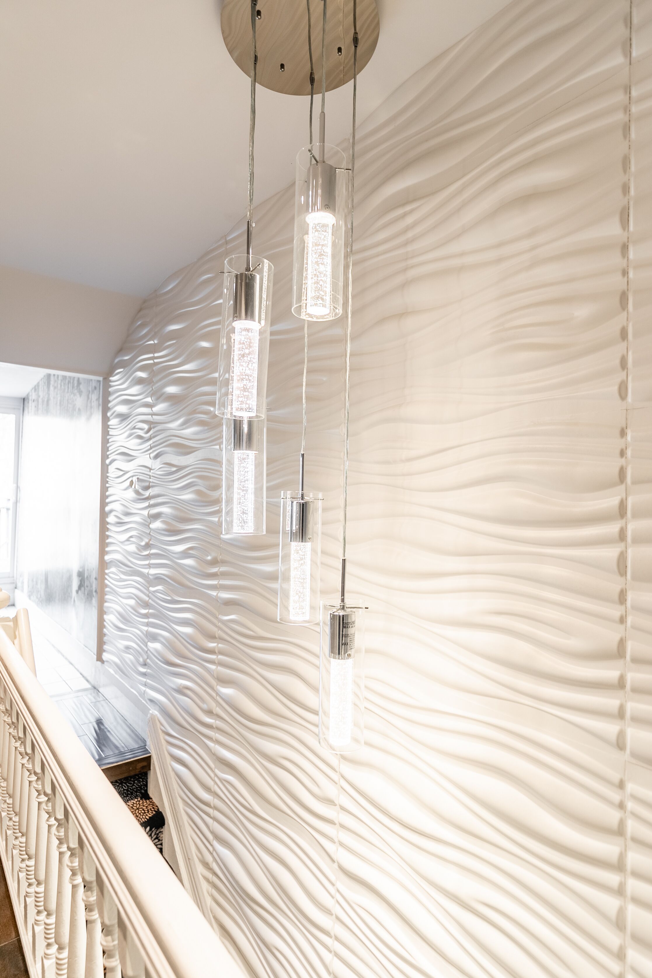 A modern interior with a wavy textured wall and a staircase with a railing.