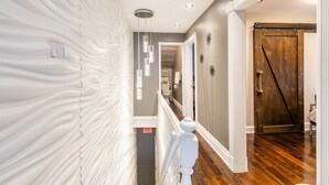 A modern interior with a textured wall, a wooden floor, a white railing, and a sliding barn-style door. - Boutique Penthouse Designer 1 BR Suite w/2 Balconies in Downtown Toronto (Toronto)