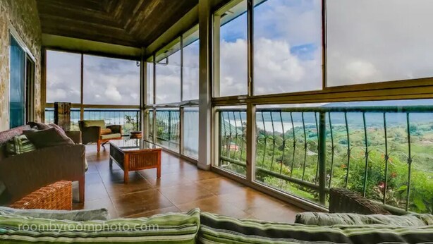 A spacious room with a large balcony, furnished with a sofa, chairs, and a coffee table.