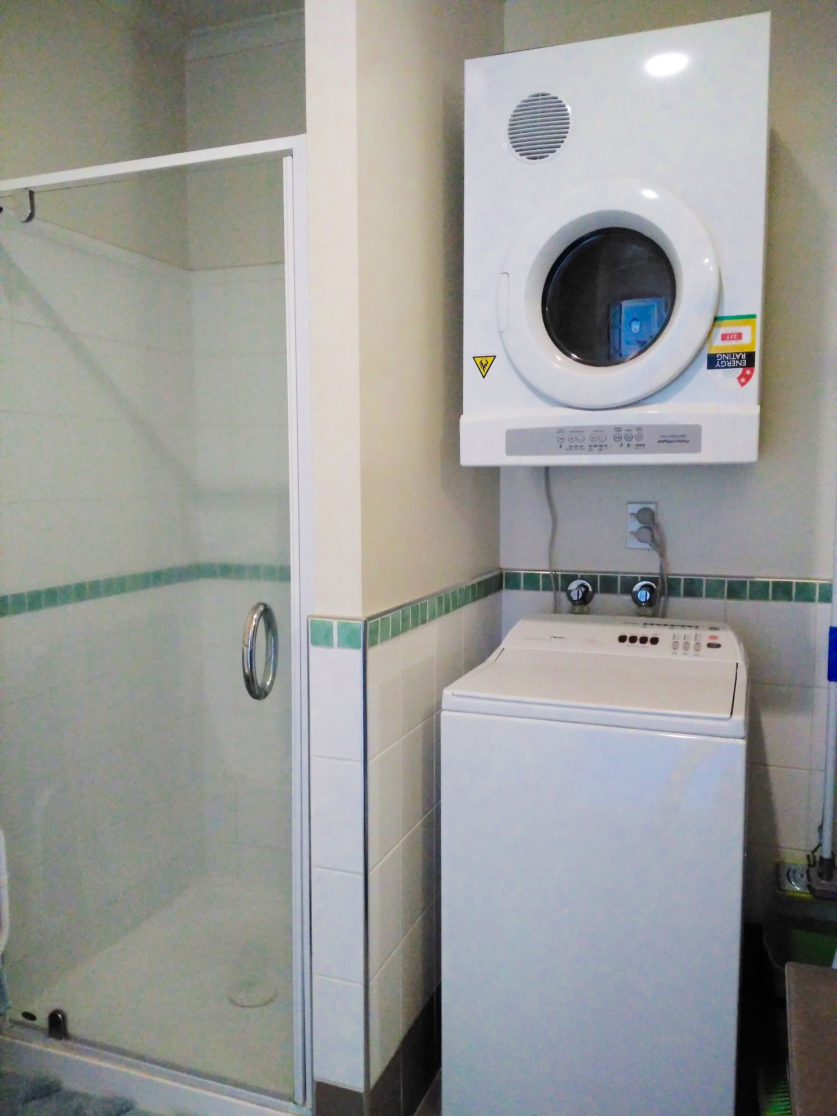 A laundry room with a front-loading washing machine and a wall-mounted dryer.