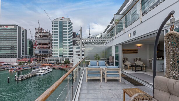 A balcony with a view of the water and cityscape, including a dock and boats. - 1BR Sub-Penthouse - Panoramic Views (Auckland)
