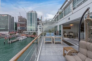 Un balcón con vista al agua y al paisaje urbano, incluyendo un muelle y barcos.