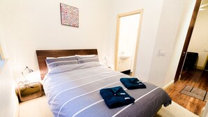 Un lit bien fait, avec une couvre-lit à rayures et deux serviettes pliées posées sur le côté.