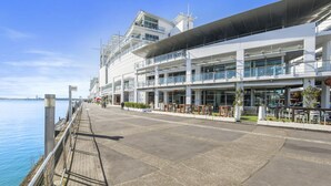 A waterfront hotel with a modern architectural design, featuring multiple balconies and large windows. - Panoramic Views - 2 Bedroom Sub-Penthouse (Auckland)