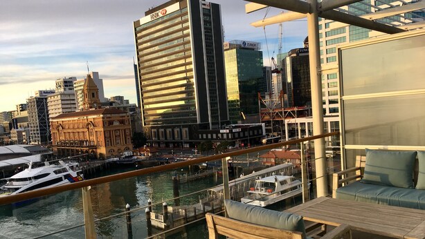 A balcony with a view of a marina and city buildings, including a HSBC building. - Princes Wharf - 1BR Comfortable Luxury (Auckland)