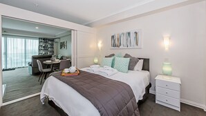 A modern hotel room with a large bed, bedside tables, a desk, and a dining area. - Princes Wharf - 1BR Comfortable Luxury (Auckland)