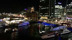 A nighttime cityscape with illuminated buildings and a marina with boats. - Princes Wharf - 1BR Comfortable Luxury (Auckland)