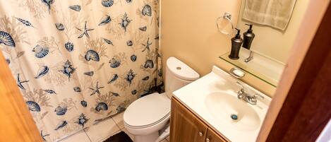 A bathroom with a toilet, sink, and mirror.