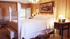 Une chambre confortable avec un lit à baldaquin, un lustre, un tableau et un plancher en bois.