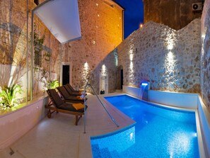 An outdoor swimming pool with stone walls and lounge chairs. - Villa in Bol with Pool and Sea View (Bol)