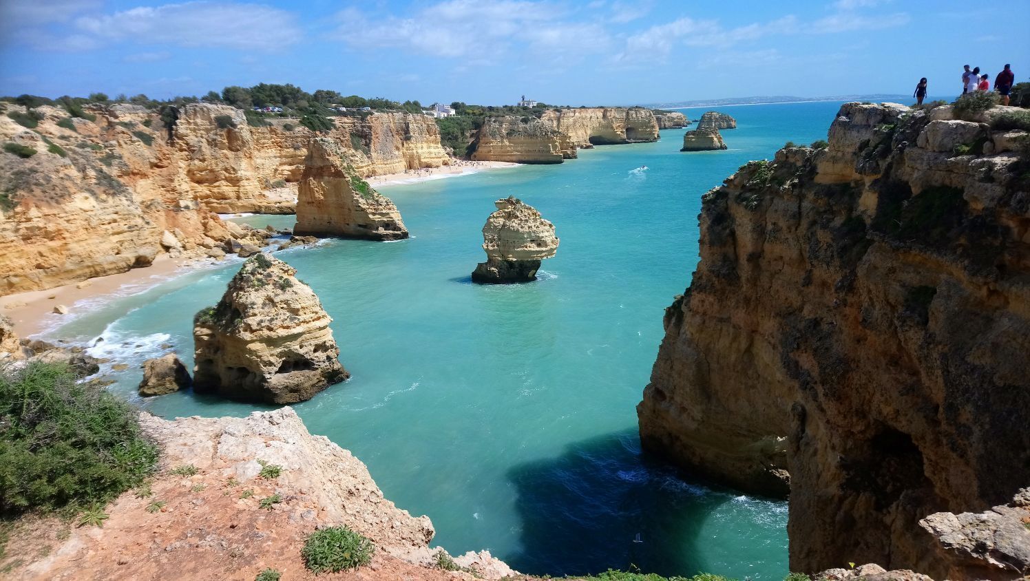 A coastal landscape with rocky cliffs and clear blue waters.