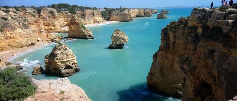 A coastal landscape with rocky cliffs and clear blue waters.