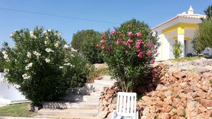 A stone staircase leading to a building with a yellow and white facade, surrounded by flowering shrubs. - Oasis of tranquility - Private villa with secure pool and large garden (Alcantarilha)