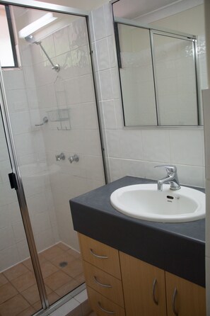 A bathroom with a glass-enclosed shower, a white sink, and a mirror above it.