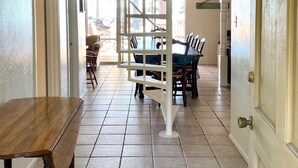A spacious dining area with a high ceiling and a staircase leading to an upper level.