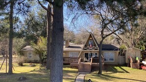 A cabin with a deck, a small porch, and a pathway leading to the entrance.