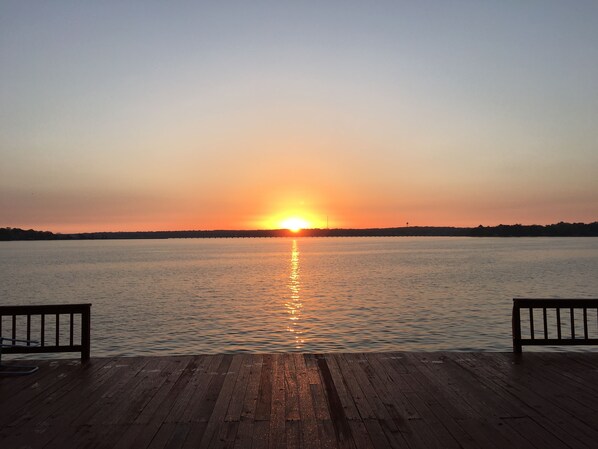 Une jetée en bois s’étendant au-dessus d’une étendue d’eau calme, avec un coucher de soleil en arrière-plan.