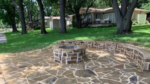 A stone patio with a fire pit in the center, surrounded by a stone wall.