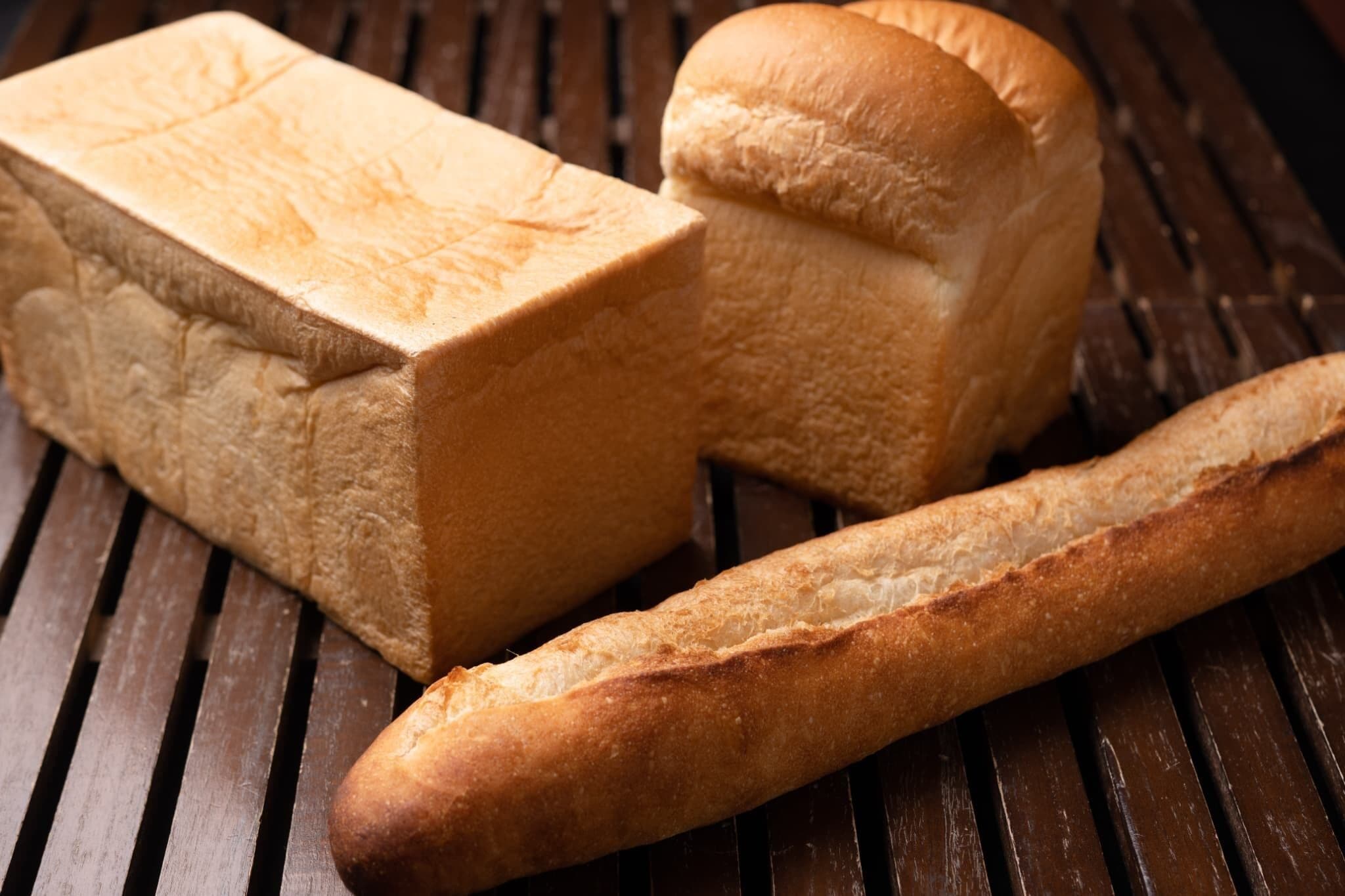 A loaf of bread and a baguette on a wooden surface.