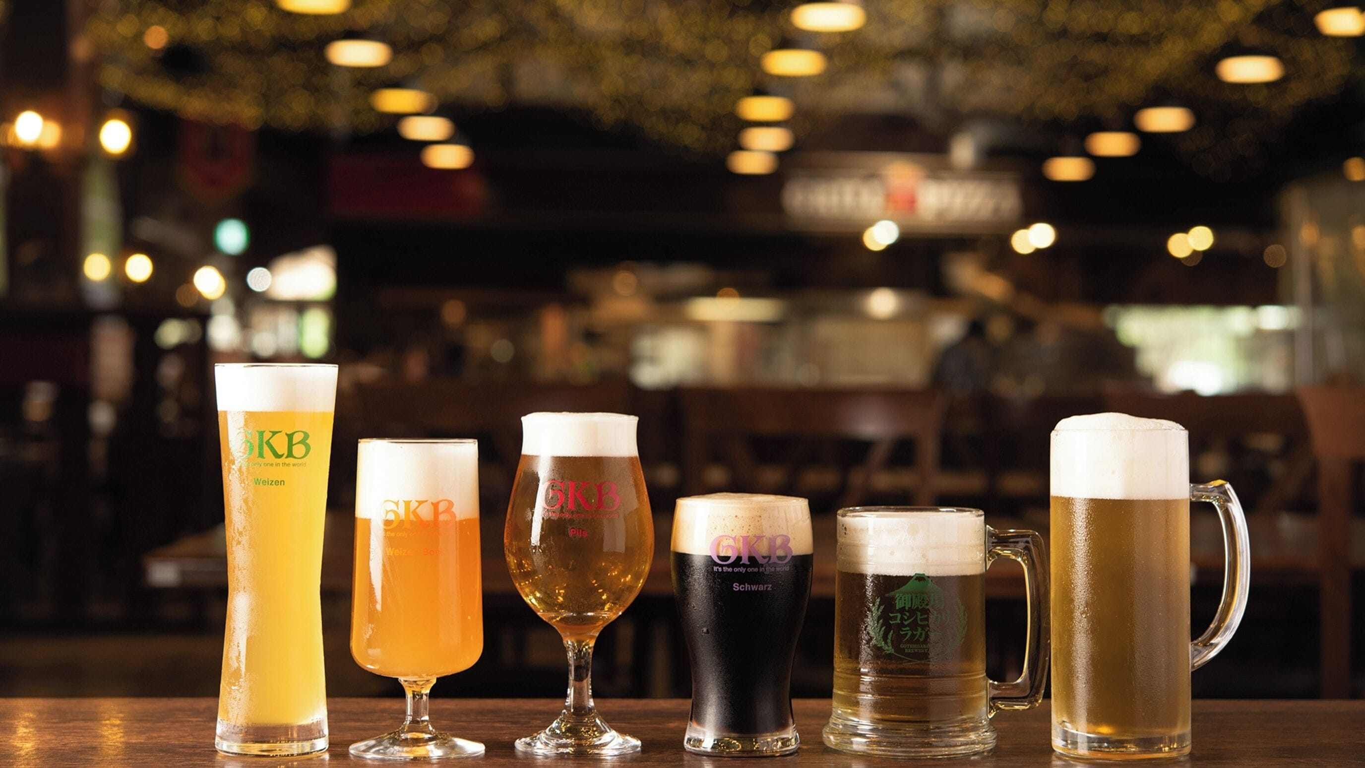 Sechs unterschiedliche Biergläser in einer Bar auf einem Tisch.
