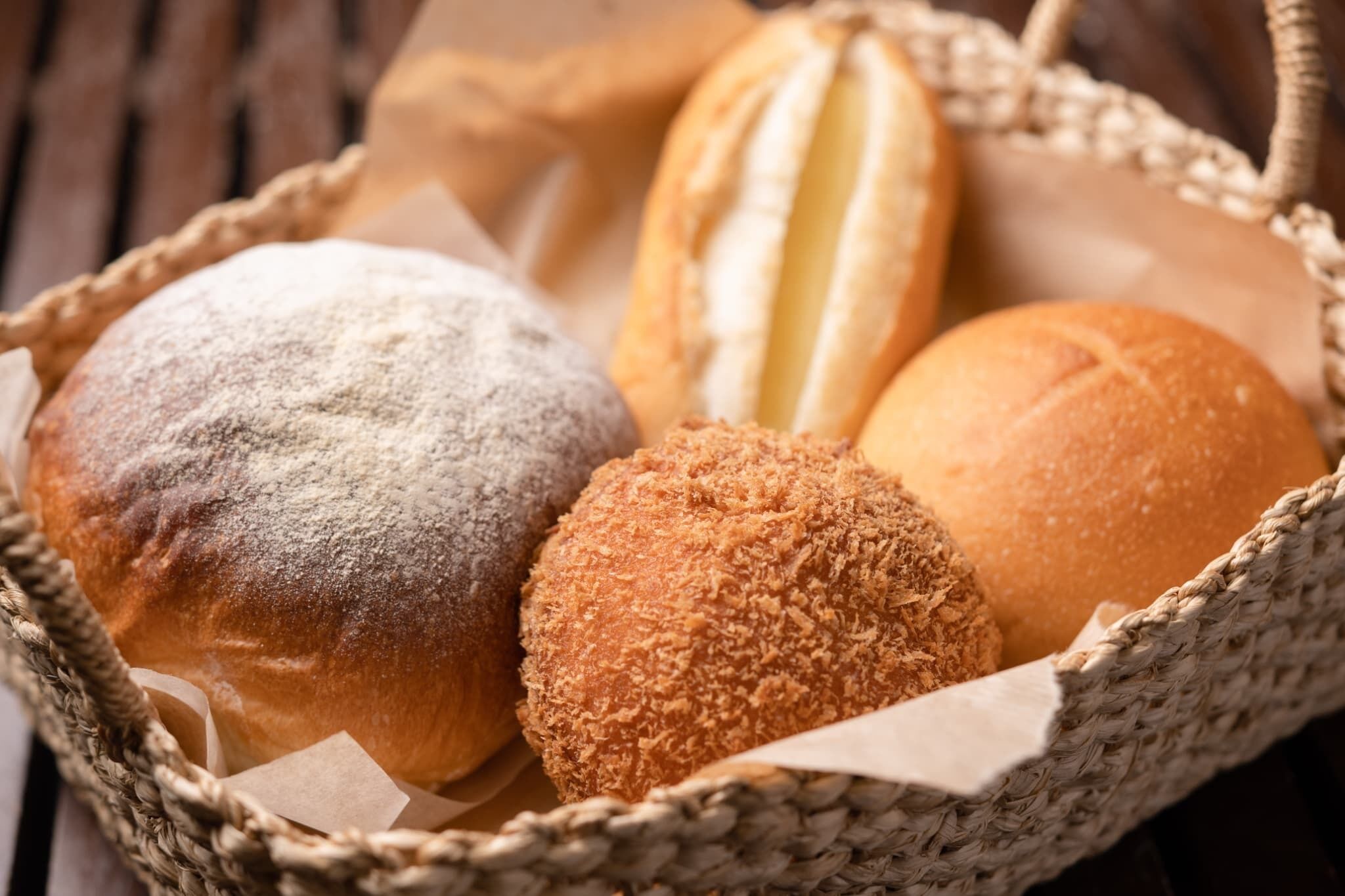 A basket containing various types of bread, including a powdered and a fried variety.