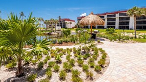 A resort with a pool, palm trees, and a thatched-roof structure. - Newly Renovated Penthouse  with Beautiful Views of the Gulf! (Sanibel)