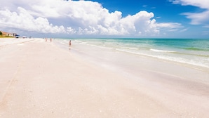 A wide sandy beach with clear blue water and a few people walking. - Newly Renovated Penthouse  with Beautiful Views of the Gulf! (Sanibel)